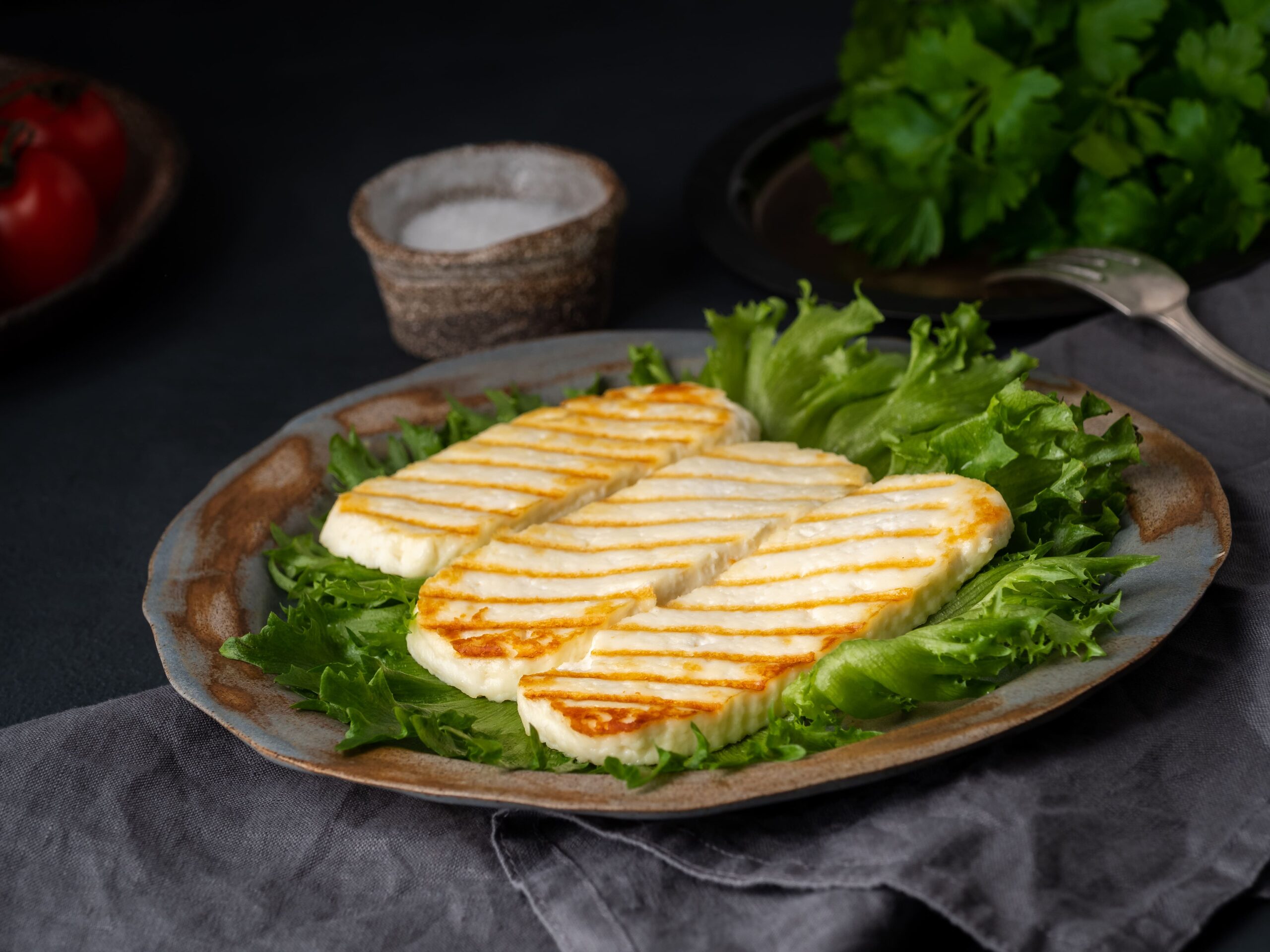 Golden brown grilled halloumi slices served on a white plate with fresh lemon wedges and herbs, perfect for a Mediterranean-inspired meal.