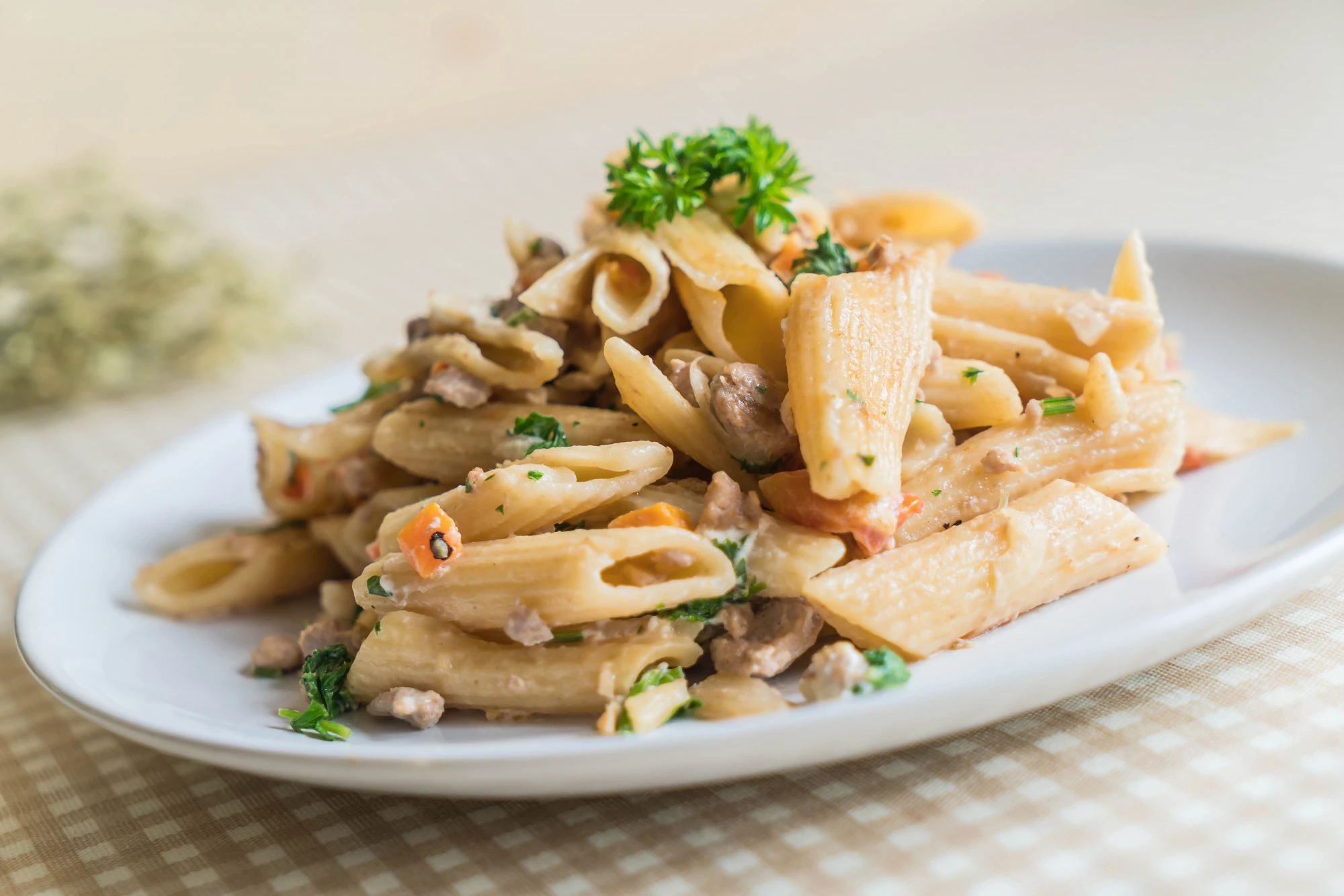 A plate of Barilla pasta, specifically penne, served in a creamy sauce with fresh parsley and vegetables, perfect for quick and easy meals.